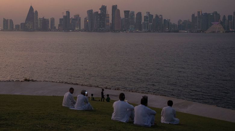A group of people sit at MIA Park, overlooking the city skyline in Doha, Qatar, on October 1, 2022.