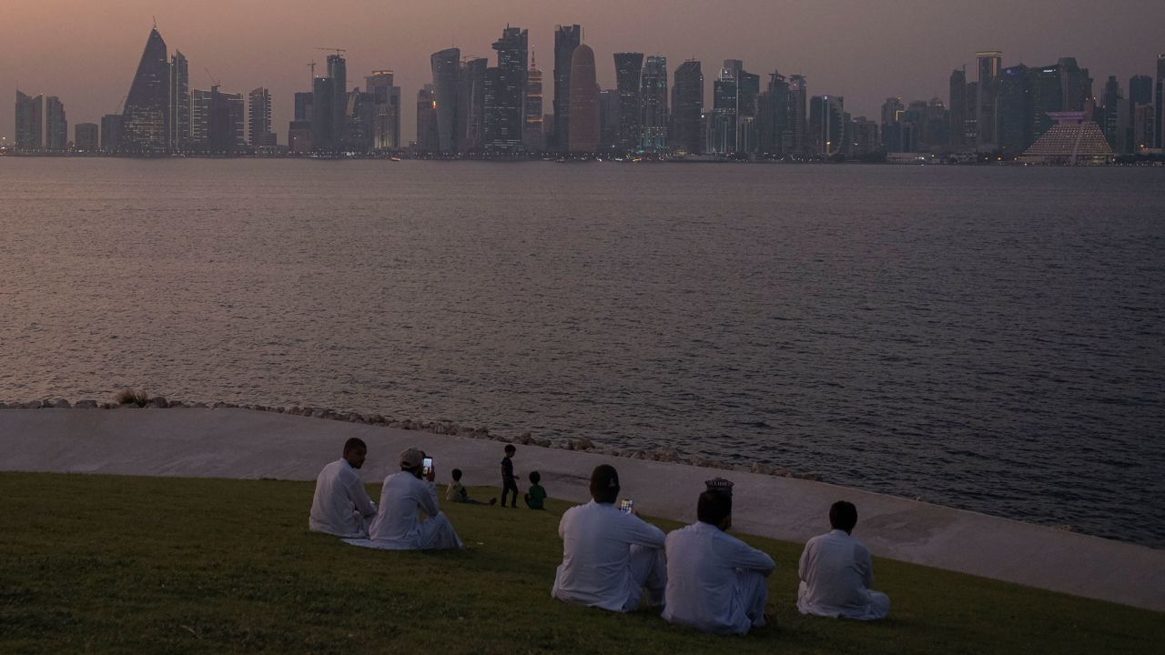 A group of people sit at MIA Park, overlooking the city skyline in Doha, Qatar, on October 1, 2022.