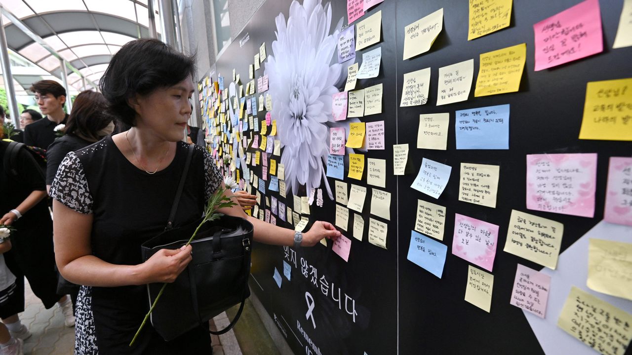 A photo taken on September 4, 2023 shows a mourner attaching a message on a memorial wall as she visits a memorial altar for an elementary school teacher who died in an apparent suicide in July, at Seoul Seoi Elementary School in Seoul. For weeks, a young South Korean teacher was bombarded with texts and calls from parents irate at how their child had been treated. Then she was found dead in her classroom. The suicide of the 23-year-old woman, in just her second year of teaching, has triggered an outpouring of grief and rage and set off widespread protests, including a rare strike, as teachers push back against what they call untenable working conditions. (Photo by Jung Yeon-je / AFP) / TO GO WITH SKorea-teachers-death, FOCUS by Kang Jin-kyu (Photo by JUNG YEON-JE/AFP via Getty Images)