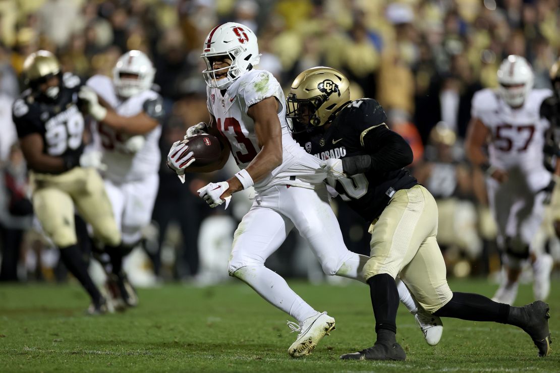Elic Ayomanor #13 of the Stanford Cardinal carries the ball carries the ball after making a catch against LaVonta Bentley #20 of the Colorado Buffaloes in the fourth quarter at Folsom Field on October 13, 2023 in Boulder, Colorado.