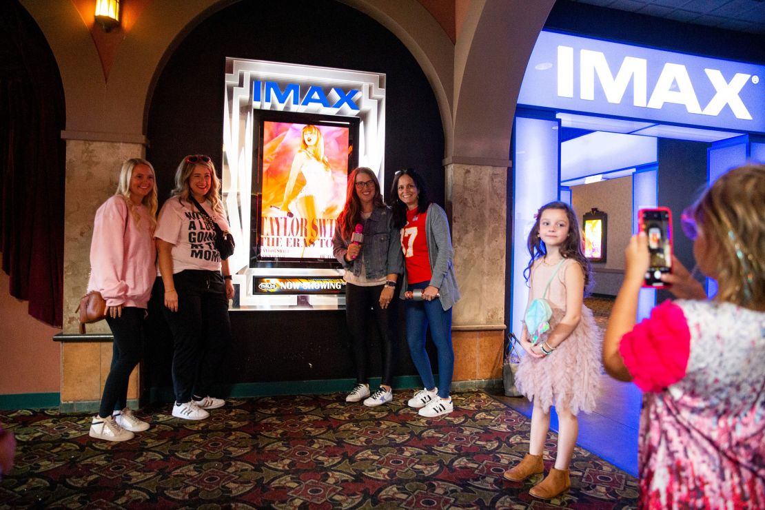 A young Taylor Swift fan takes a photo of the moms of their group next to the "Taylor Swift: The Eras Tour" poster before they go in to see the movie at Malco Paradiso Cinema Grill and IMAX in Memphis, Tenn., on Saturday, October 14, 2023.