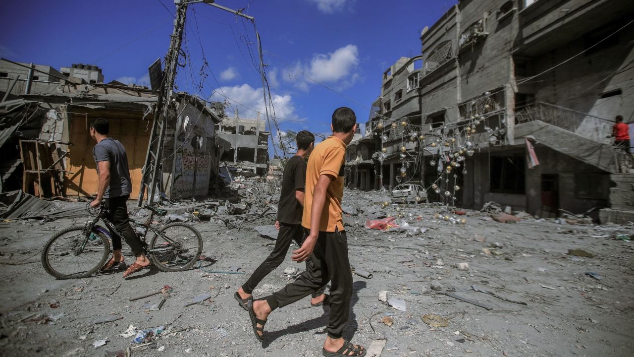 People walk amid the destruction of houses and streets in Khan Younis, located in the southern Gaza Strip.