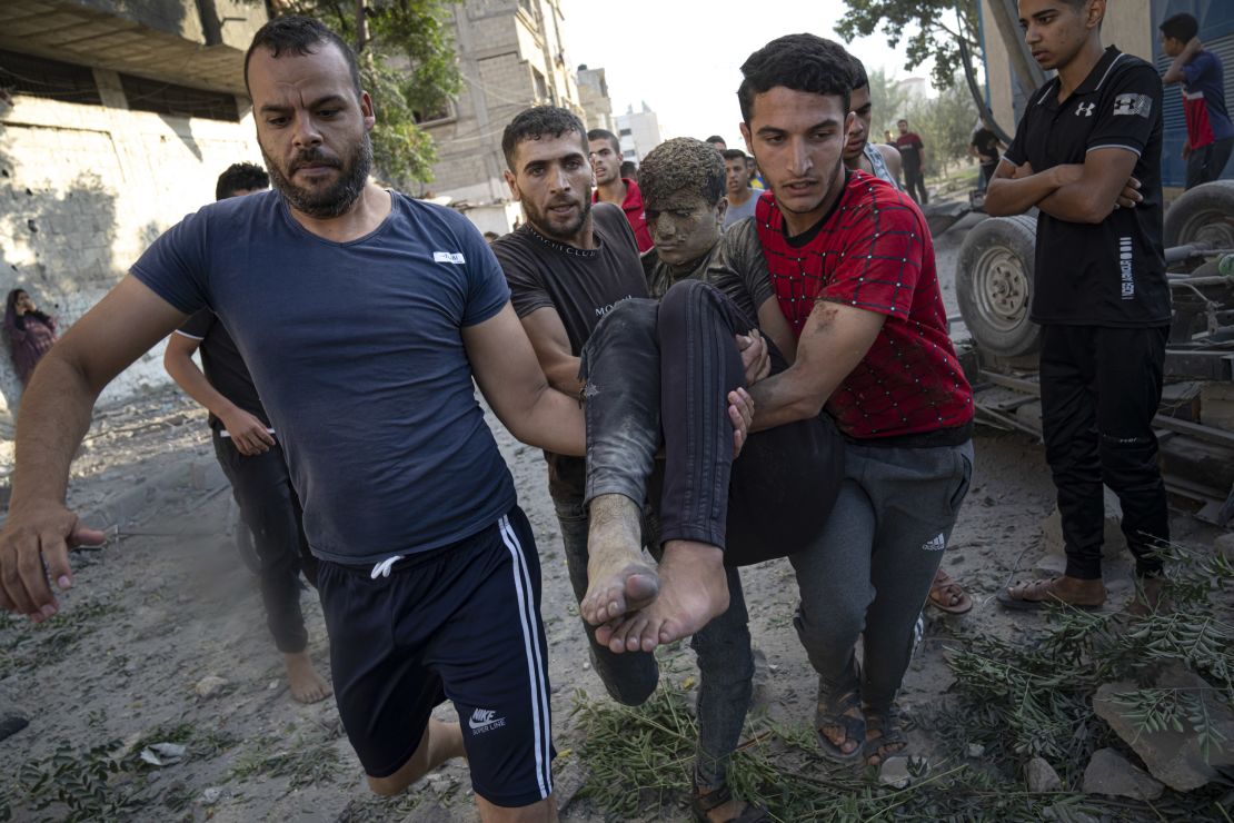 Palestinians carry a person wounded in Israeli airstrikes in Khan Younis, Gaza, on October 16.