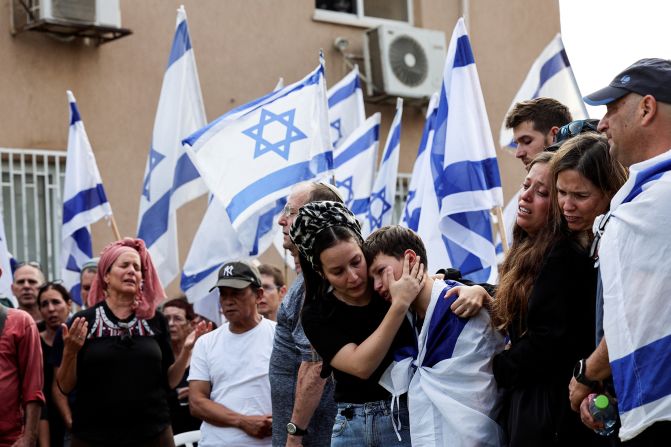 People hold Israeli flags as friends and family mourn Dor Reder at his funeral in Beit Kama, southern Israel, on October 16.
