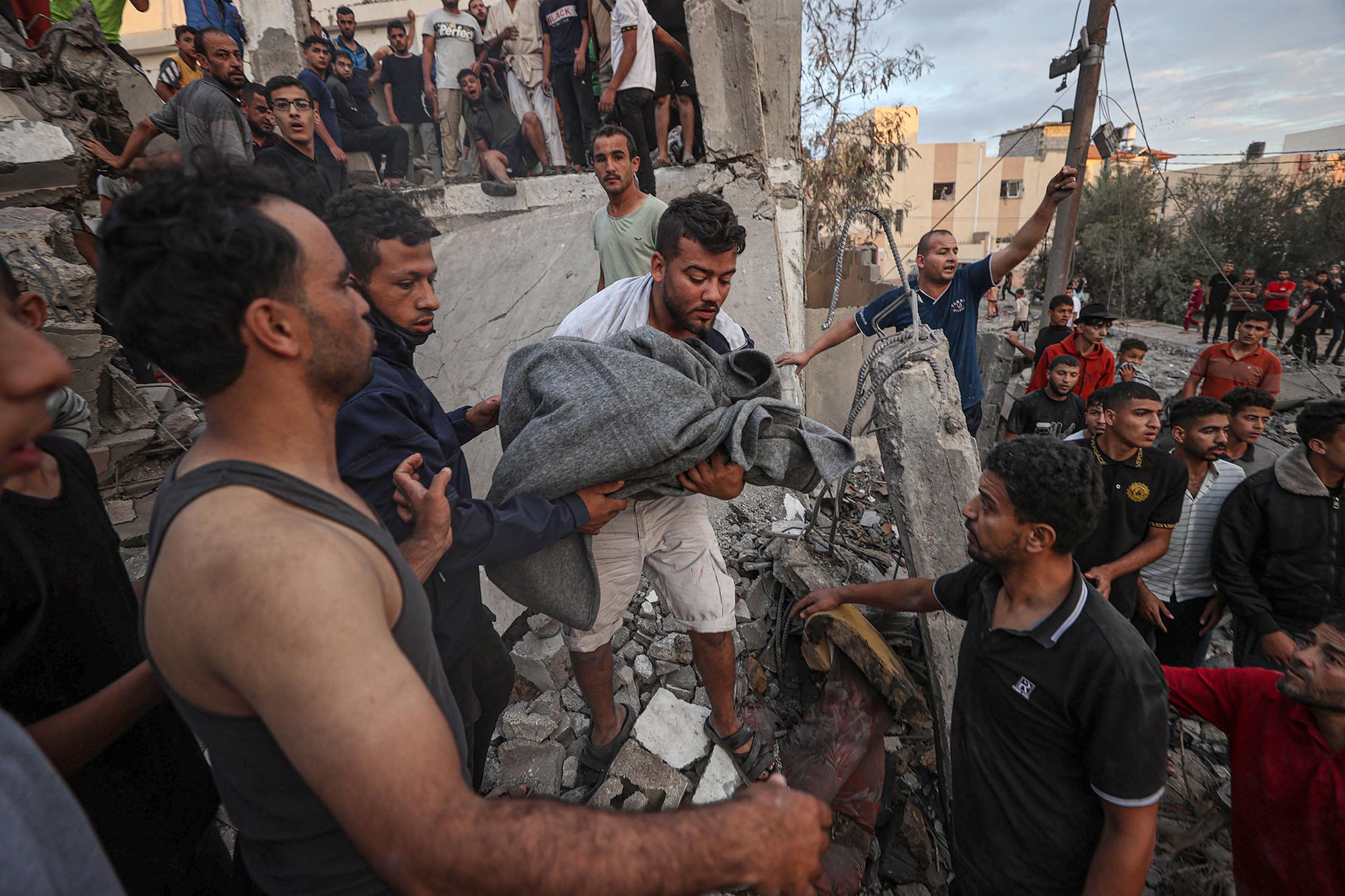 Civil defense members and residents conduct search and rescue operations amid destroyed buildings after an Israeli attack in Khan Younis, Gaza, on Tuesday, October 17,