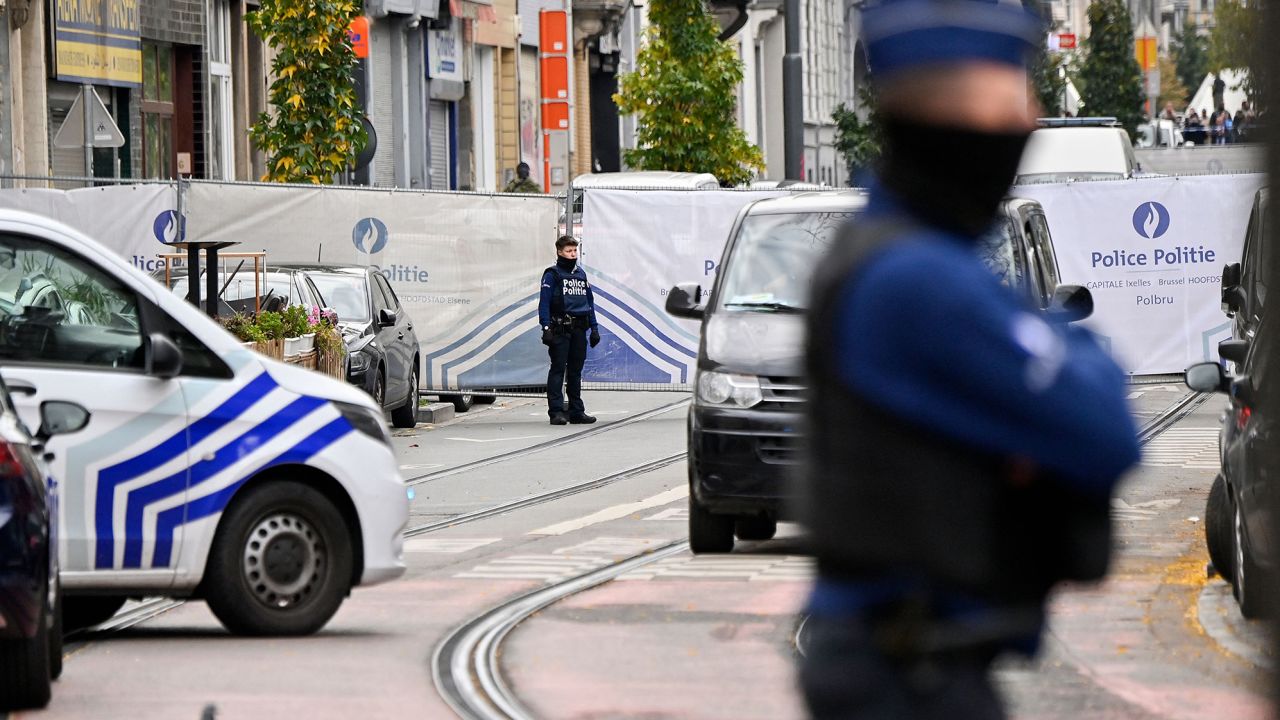 Police officers stand guard in front of the house in the Schaerbeek area of Brussels on October 17, 2023, where the suspected perpetrator of the attack in Brussels was shot dead during a police intervention.