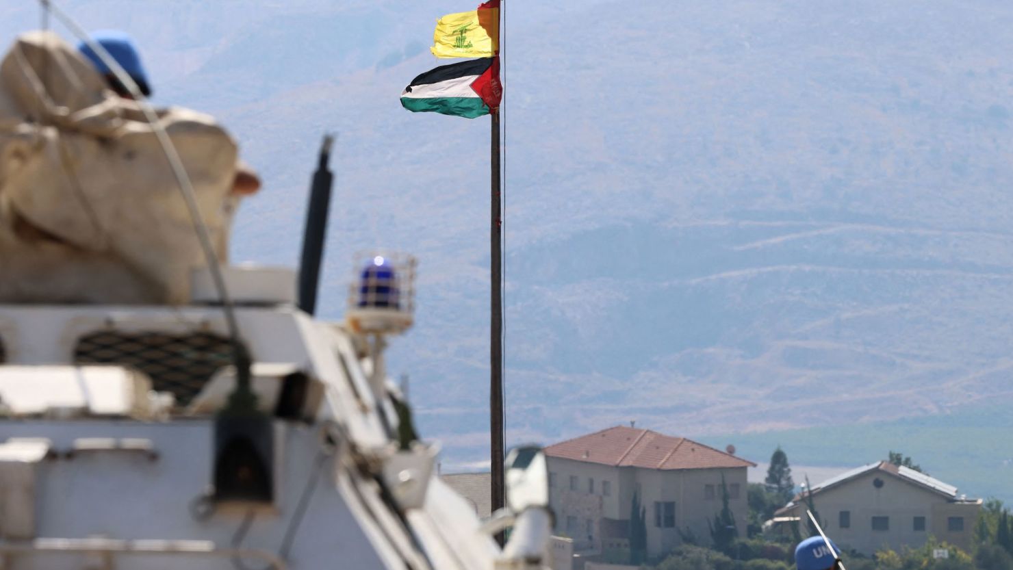 The Palestinian flag and the flag of Hezbollah wave in the wind on a pole as peacekeepers from the United Nations Interim Force in Lebanon (UNIFIL) patrol the border area between Lebanon and Israel on Hamames hill in the Khiyam area of southern Lebanon, on October 13, 2023.