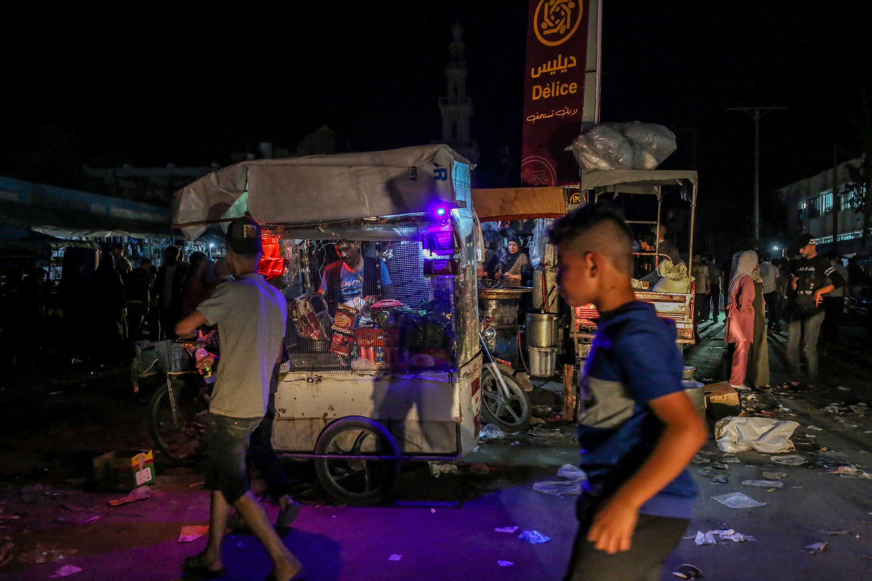 Street vendors work on a darkened street without power in Khan Younis, Gaza, on October 16.