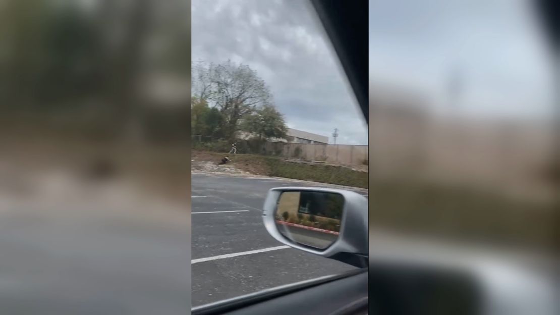 A still from witness video shows a person who appears to be Kaitlin Armstrong being pursued by an officer who has tripped behind her.
