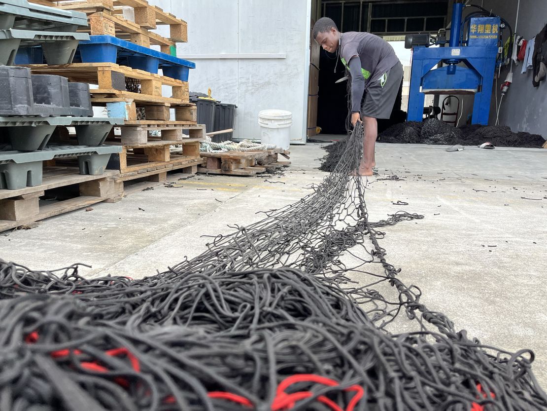 Joshua Tiatouse, a 19-year-old employee of Brikole, uses a knife to cut massive fishing nets into small panels that can be recycled and turned into new nylon products. Tiatouse says he wanted to work in a sustainable business.