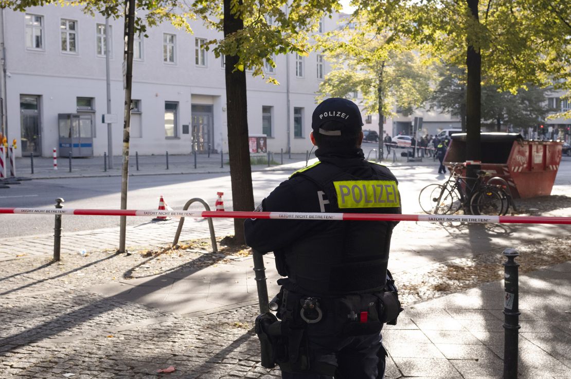 A police officer stands guard in front of the building complex.