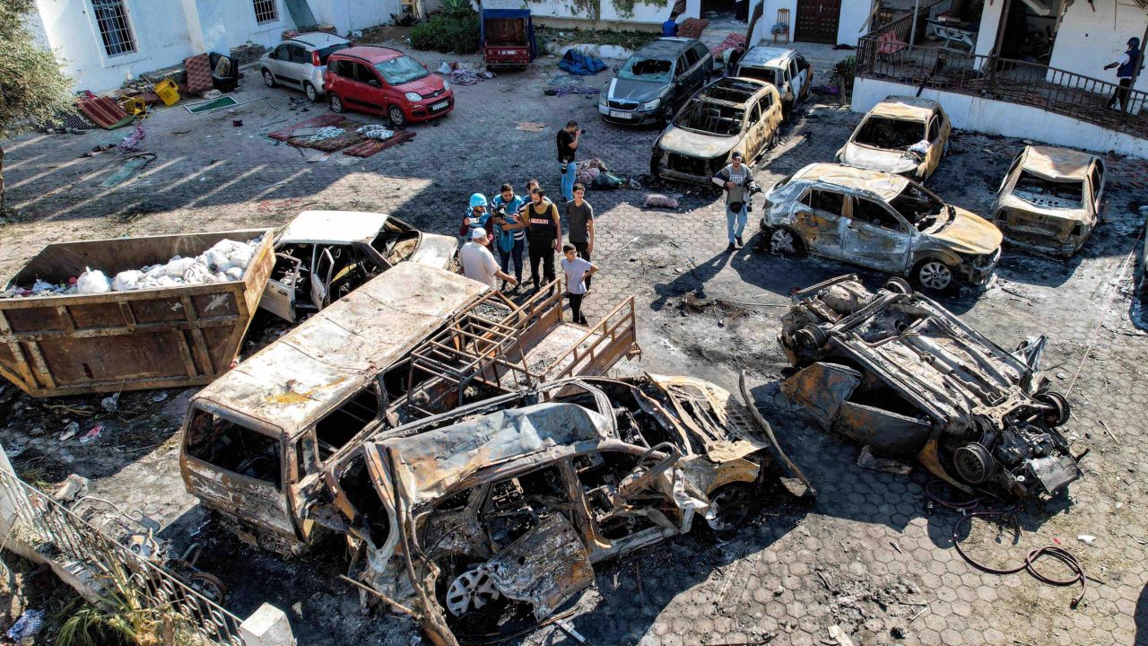 This aerial view shows people standing before destroyed buildings at the site of the Ahli Arab hospital in central Gaza on October 18, 2023 in the aftermath of an overnight strike there. A blast ripped through a hospital in war-torn Gaza killing hundreds of people late on October 17, sparking global condemnation and angry protests around the Muslim world. Israel and Palestinians traded blame for the incident, which an "outraged and deeply saddened" US President Joe Biden denounced while en route to the Middle East. (Photo by Shadi AL-TABATIBI / AFP) (Photo by SHADI AL-TABATIBI/AFP via Getty Images)