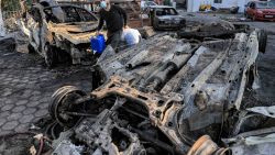 A man walks with salvaged items past destroyed vehicles at the site of the Ahli Arab hospital in central Gaza on October 18, 2023 in the aftermath of an overnight strike there. A blast ripped through a hospital in war-torn Gaza killing hundreds of people late on October 17, sparking global condemnation and angry protests around the Muslim world. Israel and Palestinians traded blame for the incident, which an "outraged and deeply saddened" US President Joe Biden denounced while en route to the Middle East. (Photo by AFP) (Photo by -/AFP via Getty Images)