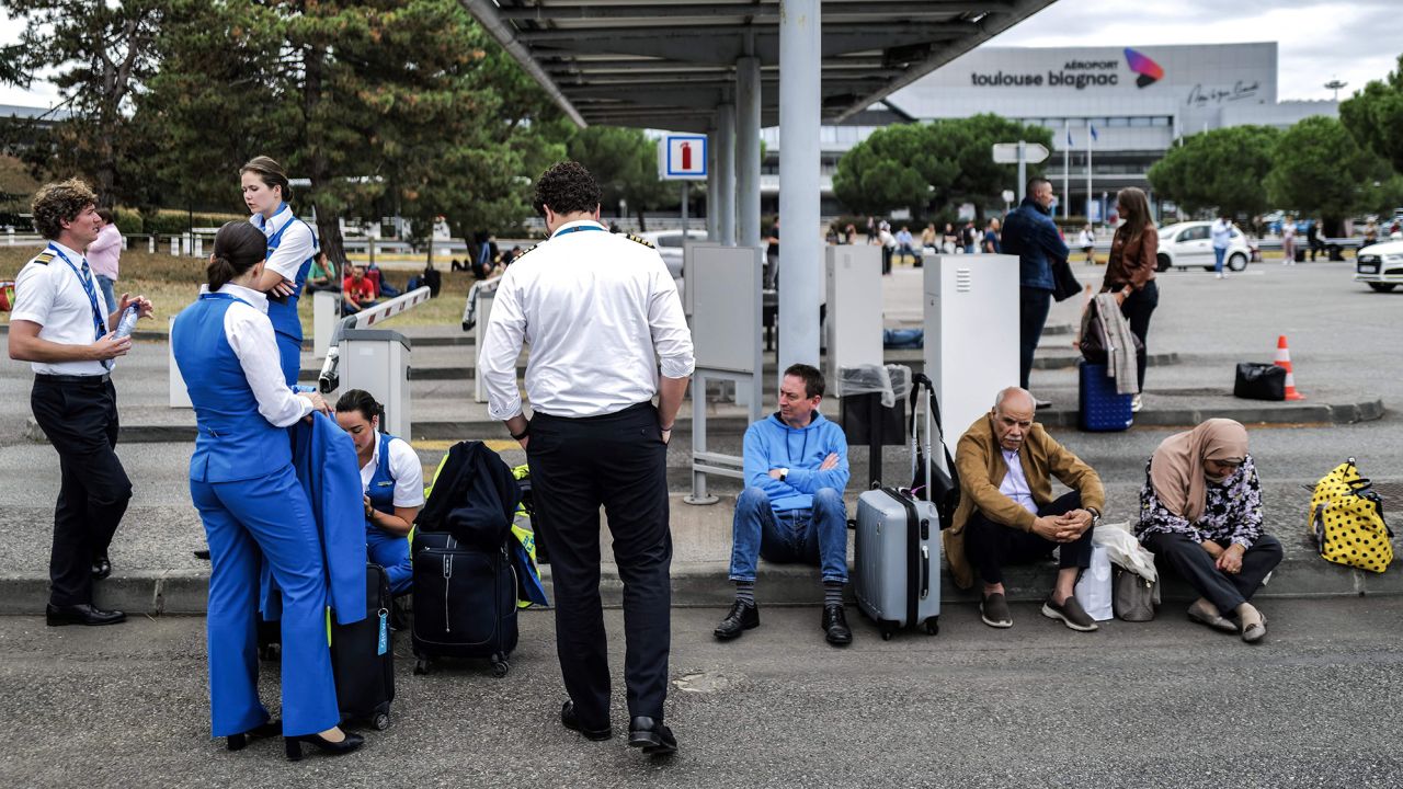 Passengers and airline staff wait outside the Toulouse-Blagnac Airport in Blagnac, southwestern France, on October 18, 2023, after the airport has been evacuated.