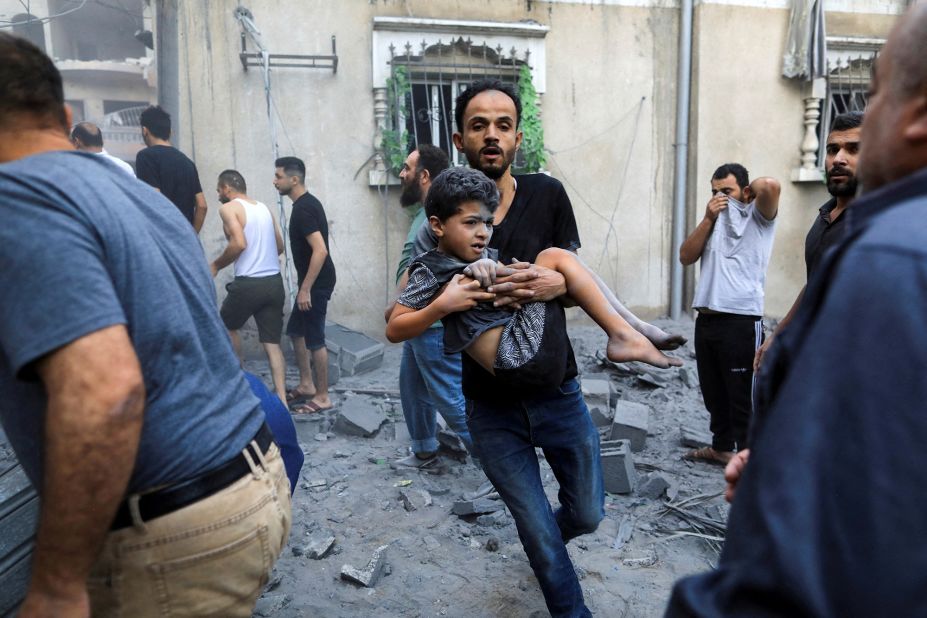 A man carries a wounded child at the site of an Israeli strike in Khan Younis, Gaza, on October 19.