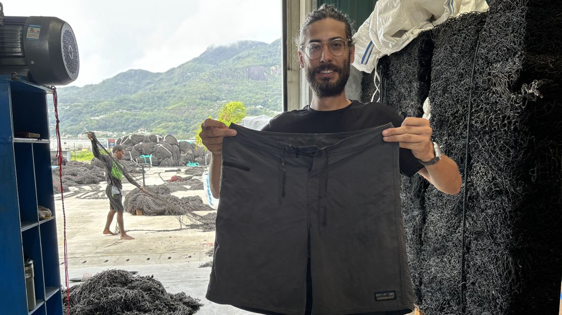 Kyle de Bouter holds board shorts made of recycled Nylon fishing nets similar to the kind he is recycling. His company plans to create similar products made entirely from nets recycled in the Seychelles. His small business, Brikole, is an example of sustainable businesses model Seychelles officials would like to support as part of their 