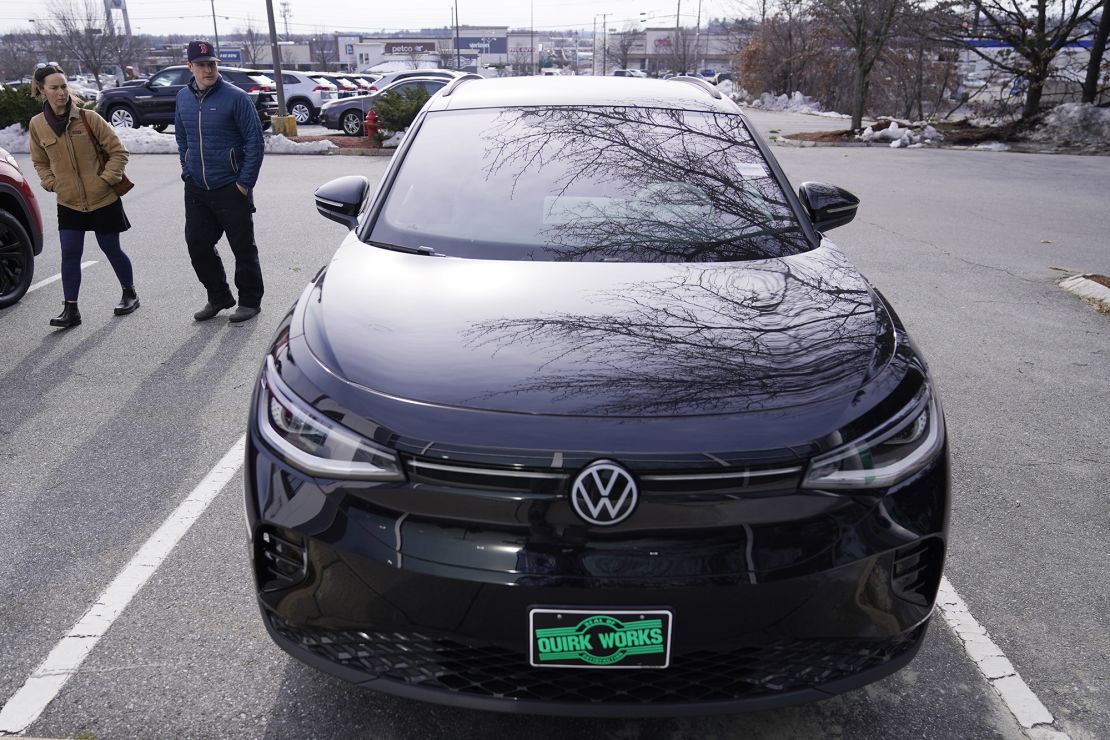 A couple looks at a Volkswagen ID.4 electric vehicle while shopping at a new car dealership.