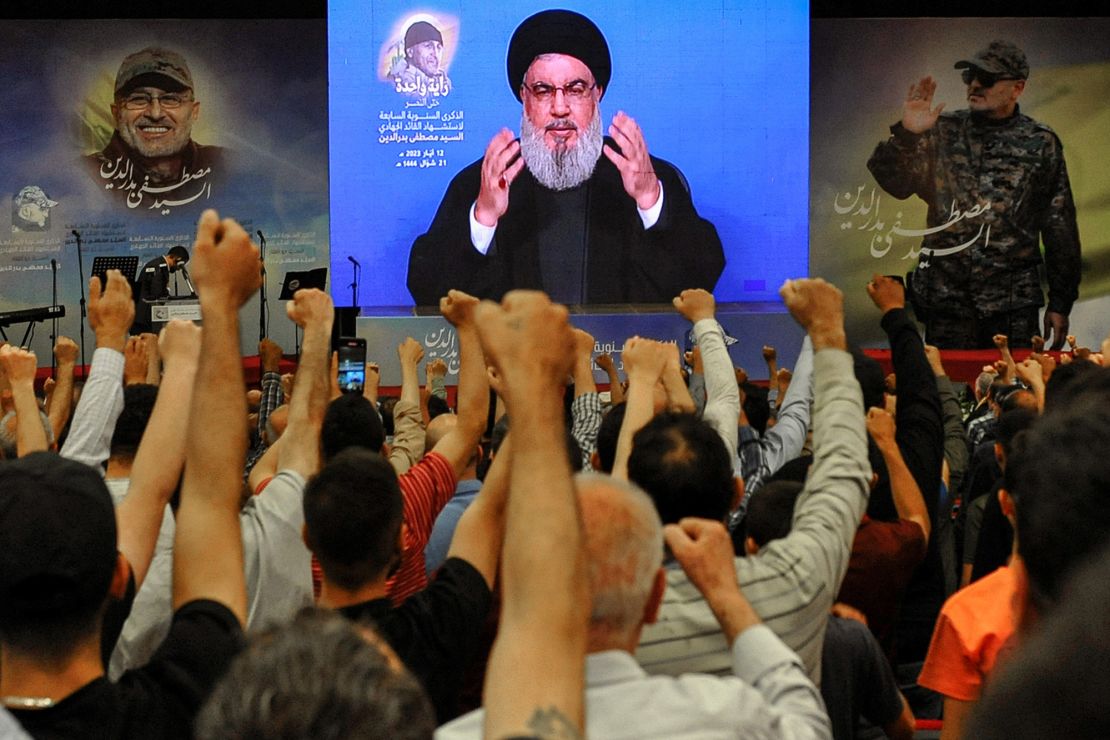 Hezbollah supporters raise their fists to salute party leader Hassan Nasrallah in May 2023.