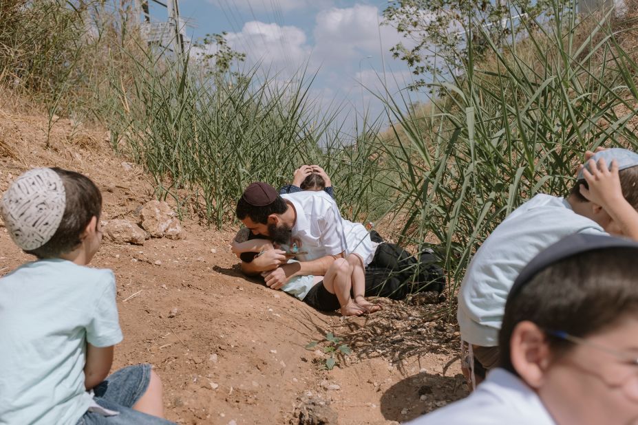 Israelis take cover after hearing warning sirens of incoming rockets fired from Gaza in Rehovot, Israel, on Friday, October 13.