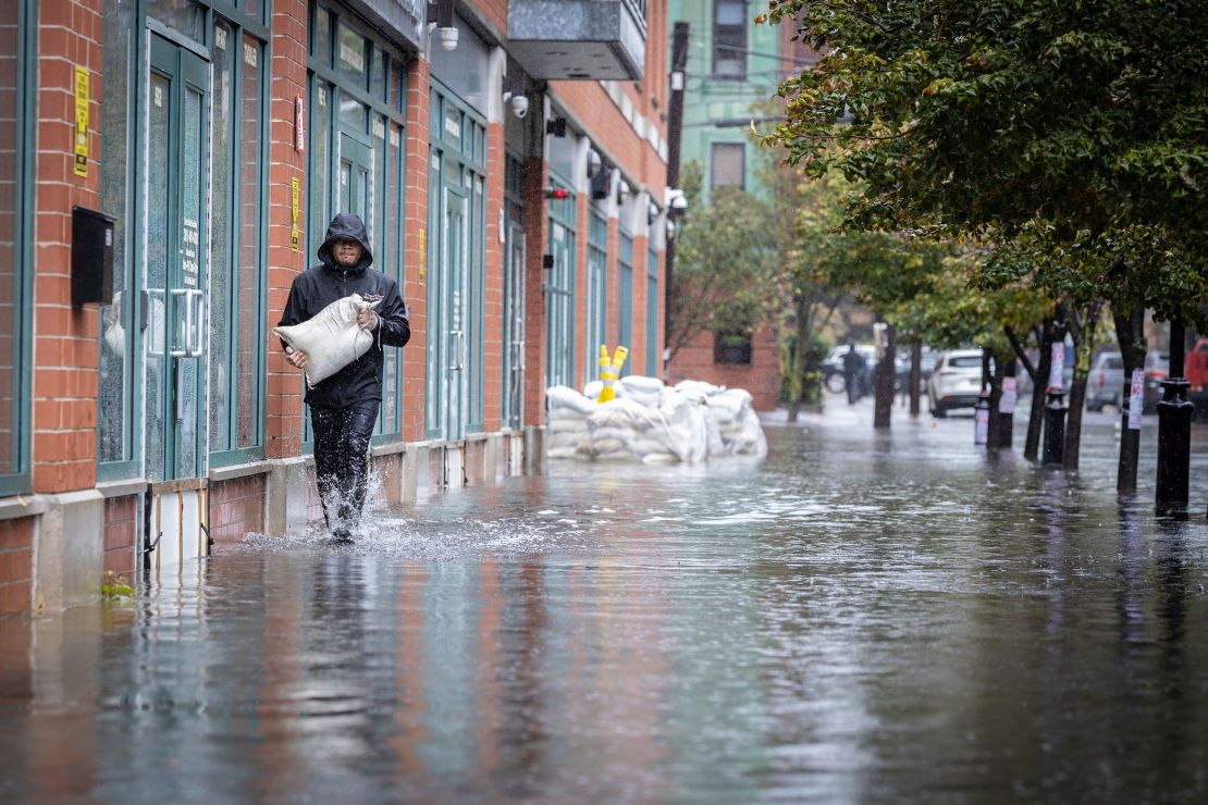 Човек носи чували с пясък през вода, защото пороен дъжд аргументи наводняване на улици в Хобокен, Ню Джърси, в петък, 29 септември 2023 година 