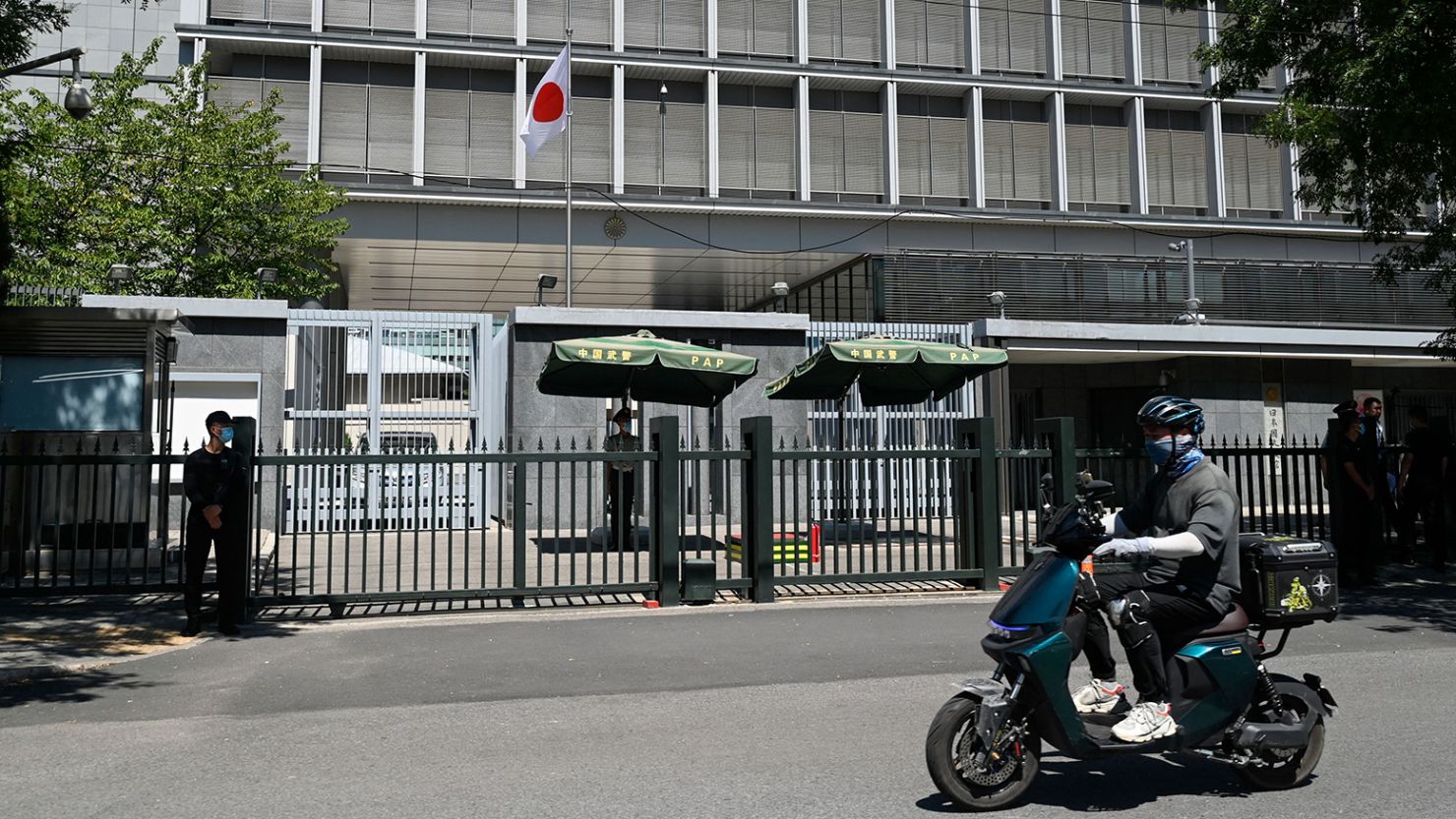 A man rides his motorcycle past the entrance of the Japanese embassy in Beijing on August 29, 2023. 
