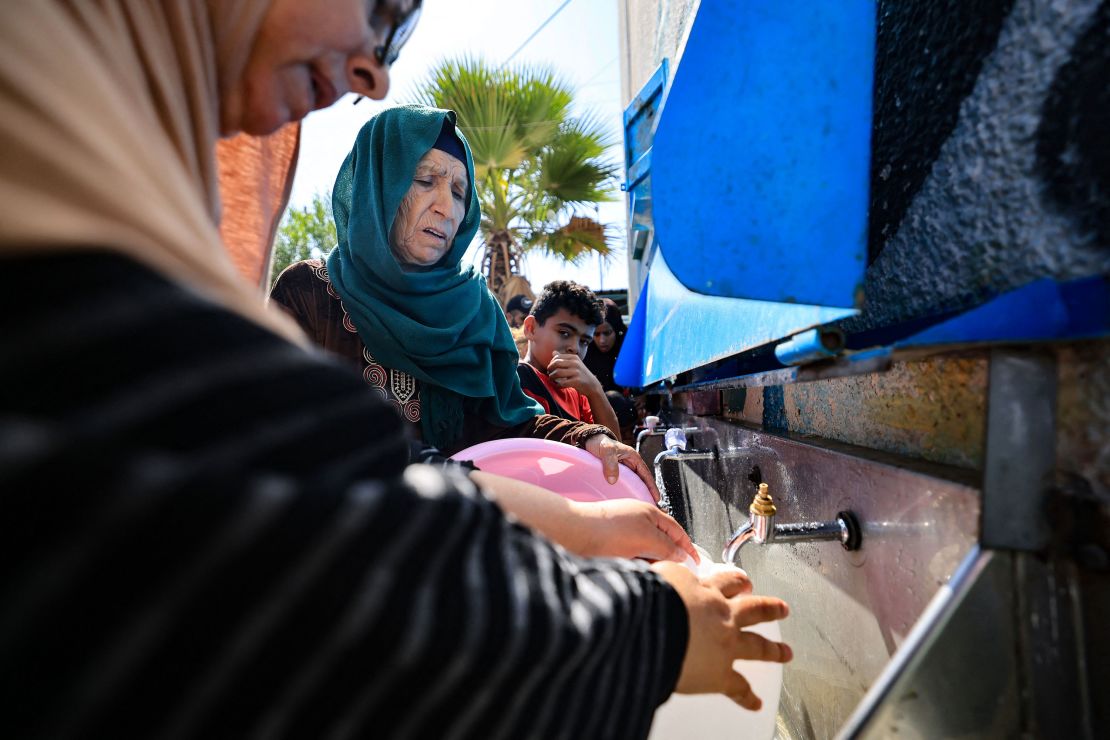 Displaced Palestinians fetch drinking water in the yard of a UNRWA school in Khan Yunis, in the southern Gaza Strip on October 20, 2023.