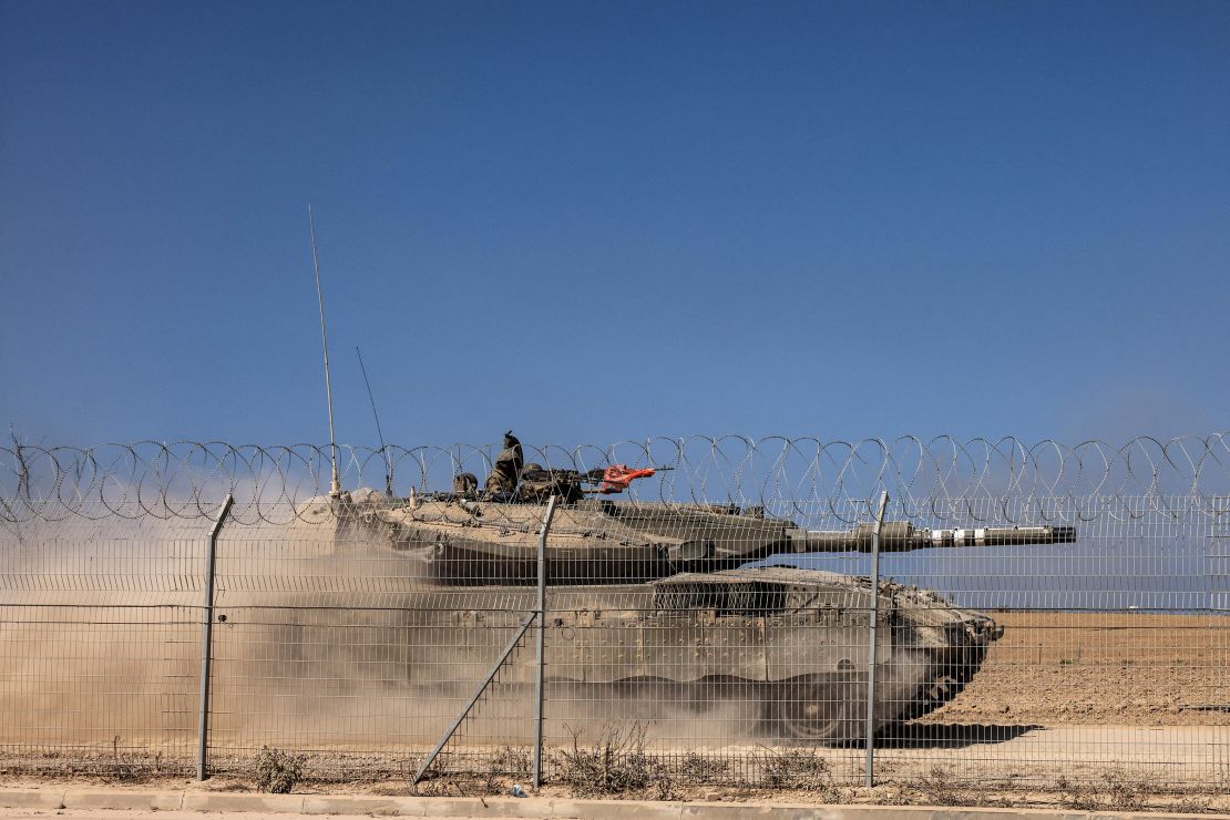 An Israeli Merkava tank drives past a fence near Kibbutz Beeri, close to the border with Gaza on October 20, 2023.