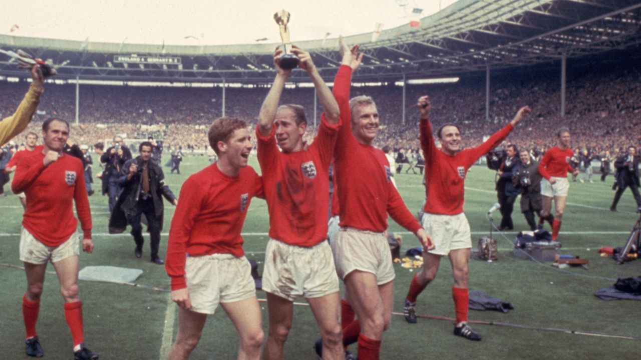 Bobby Charlton raises the Jules Rimet trophy in the air  following England's 4-2 victory after extra time over West Germany in the World Cup Final at Wembley Stadium, 30th July 1966. Amongst his team mates celebrating with him are goalkeeper Gordon Banks, Alan Ball on his right and team captain Bobby Moore (1941 - 1993) at his left.