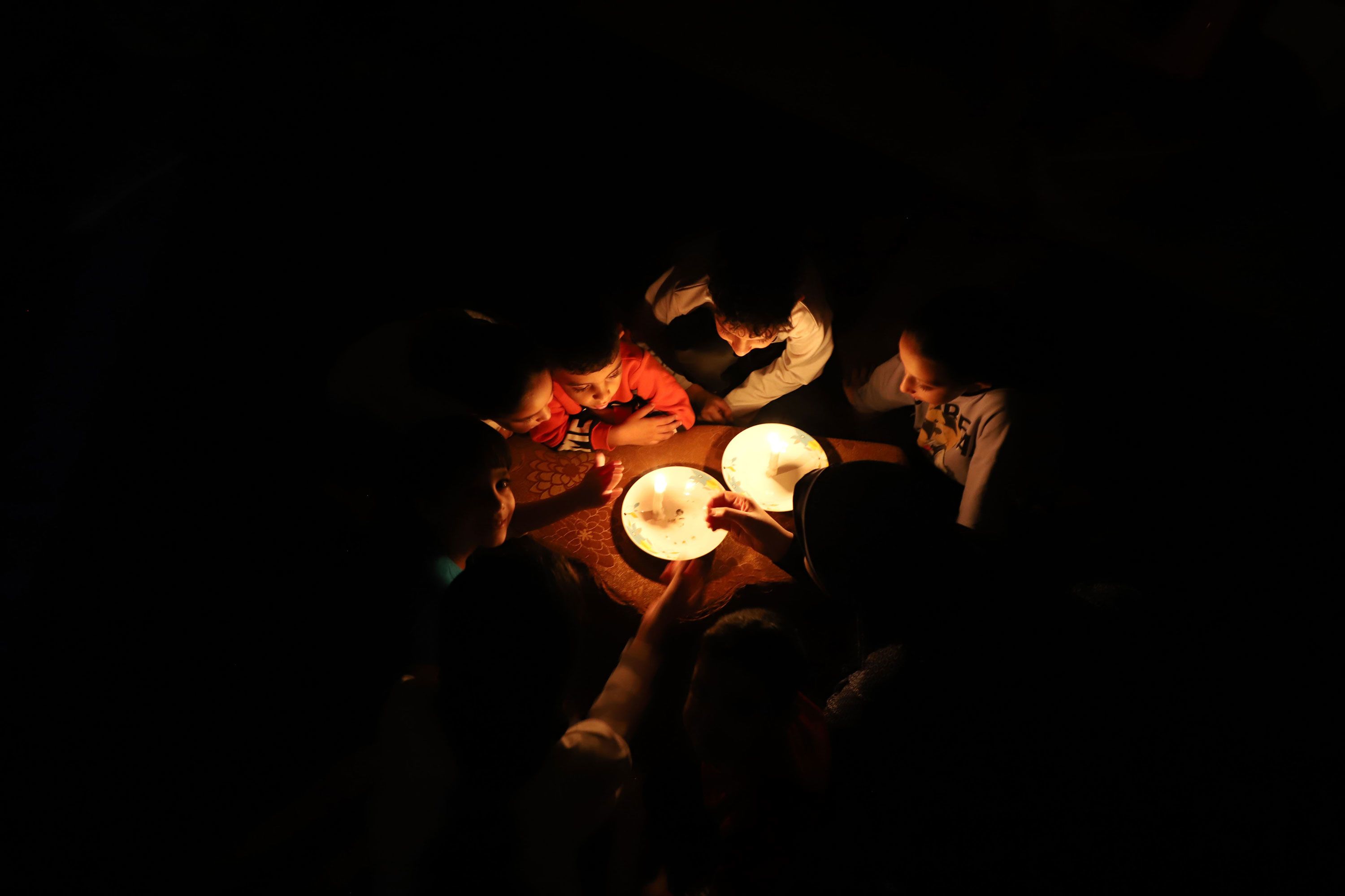 Children use candles for lighting in Khan Younis, Gaza, on Friday, October 20.