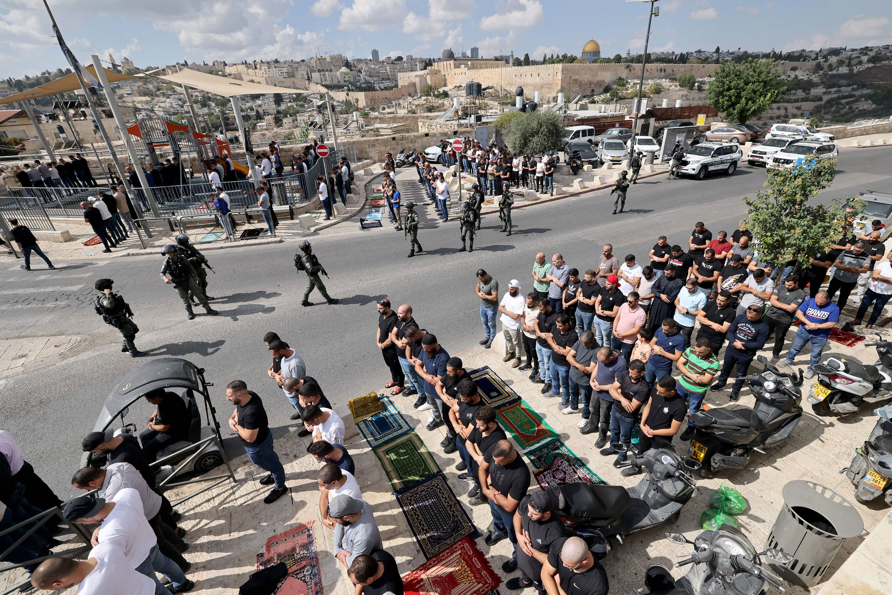 Muslim Palestinians take part in Friday noon prayers as Israeli police look on in the East Jerusalem neighborhood of Ras al-Amud, on October 20.