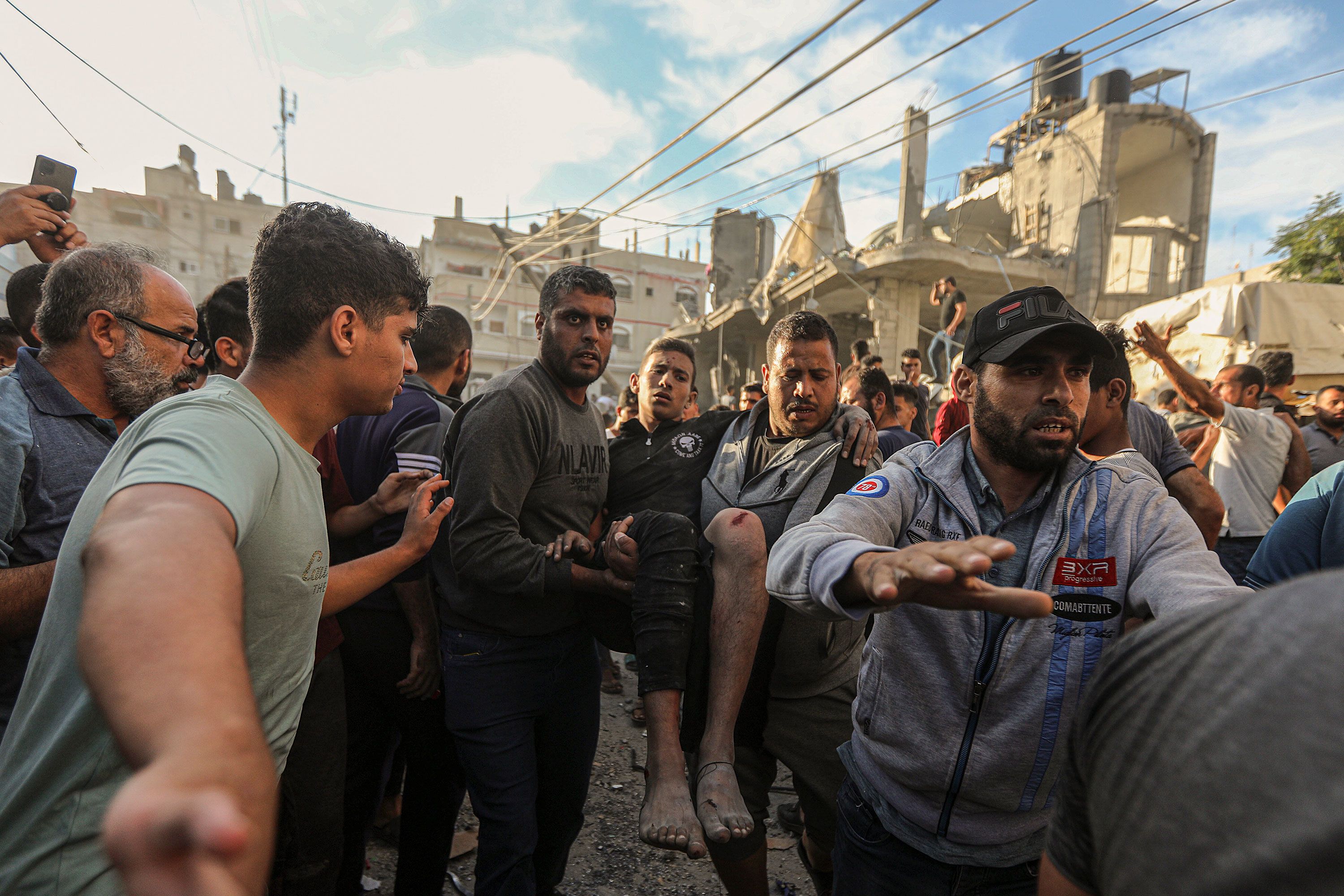 Injured civilians are recovered from the rubble of a destroyed house following Israeli air strikes near a UNRWA school housing displaced people in Khan Younis, Gaza, on Saturday, October 21. 