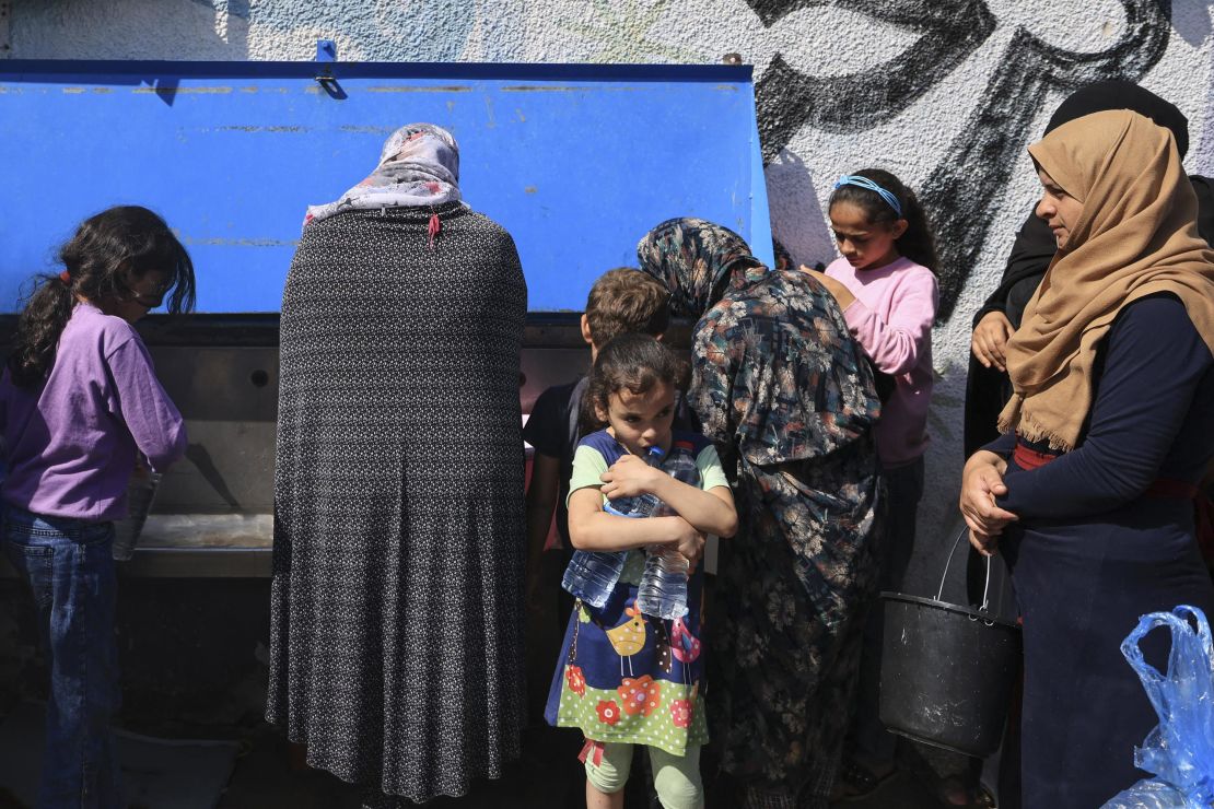 Displaced people fetch drinking water in the yard of an UNRWA school in Khan Younis, in southern Gaza, on October 20, 2023.