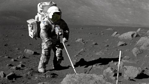 Geologist-Astronaut Harrison Schmitt, Apollo 17 lunar module pilot, uses an adjustable sampling scoop to retrieve lunar samples during the second extravehicular activity (EVA-2), at Station 5 at the Taurus- Littrow landing site. The cohesive nature of the lunar soil is born out by the "dirty" appearance of Schmitt's space suit. A gnomon is atop the large rock in the foreground. The gnomon is a stadia rod mounted on a tripod, and serves as an indicator of the gravitational vector and provides accurate vertical reference and calibrated length for determining size and position of objects in near-field photographs. The color scale of blue, orange and green is used to accurately determine color for photography. The rod of it is 18 inches long. The scoop Dr. Schmitt is using is 11 3/4 inches long and is attached to a tool extension which adds a potential 30 inches of length to the scoop. The pan portion, blocked in this view, has a flat bottom, flanged on both sides with a partial cover on the top. It is used to retrieve sand, dust and lunar samples too small for the tongs. The pan and the adjusting mechanism are made of stainless steel and the handle is made of aluminum.