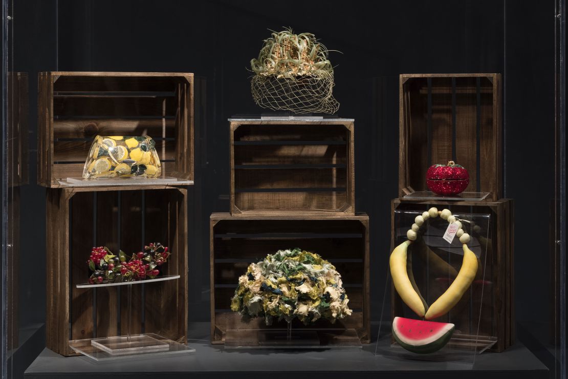 A display in the "Food & Fashion" exhibition features accessories including a lemon-patterned Lucite handbag (top left) by artist Joyce Francis, a corn cob-topped hat (center) by the milliner Benjamin B. Green-Field and a chunky necklace resembling watermelon, bananas and grapes (bottom right).