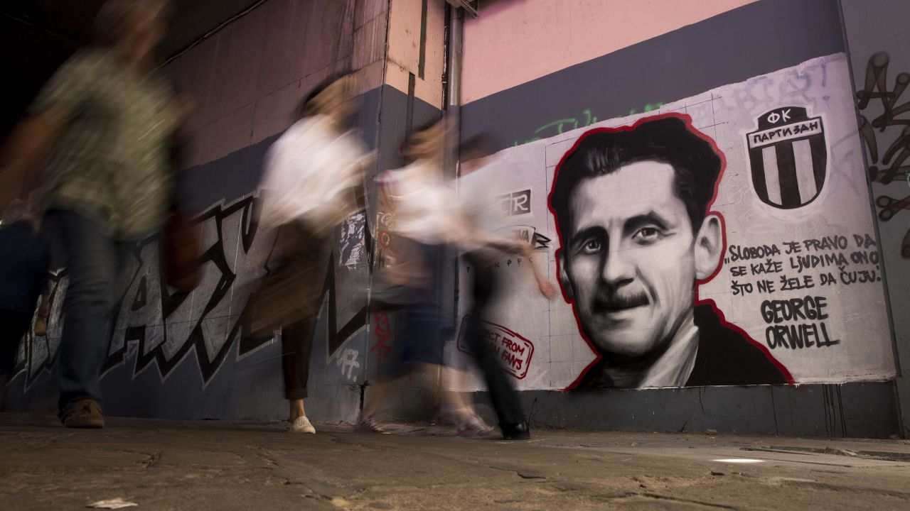 People walk past a mural painted by an artist of the Grobarski Trash Romantizam (GTR) group, depicting British novelist George Orwell with the reading "Freedom is the right to tell people what they do not want to hear", in Belgrade on May 8, 2018. - They are "Gravediggers' Trash Romantism" and cover the walls of Belgrade with their love for Partizan, one of two main Serbian clubs, far from the image of ultranationalism and violent Balkan fans. In Belgrade, many willingly offer their theory what will make a supporter a soldier of the army of "Grobari" (Gravediggers) of Partizan or "Cigani" (Gypsies) of Red Star, two giants of Yugoslav and Serbian football, founded at the end of World War II. (Photo by OLIVER BUNIC / AFP) / RESTRICTED TO EDITORIAL USE - MANDATORY MENTION OF THE ARTIST UPON PUBLICATION - TO ILLUSTRATE THE EVENT AS SPECIFIED IN THE CAPTION        (Photo credit should read OLIVER BUNIC/AFP via Getty Images)