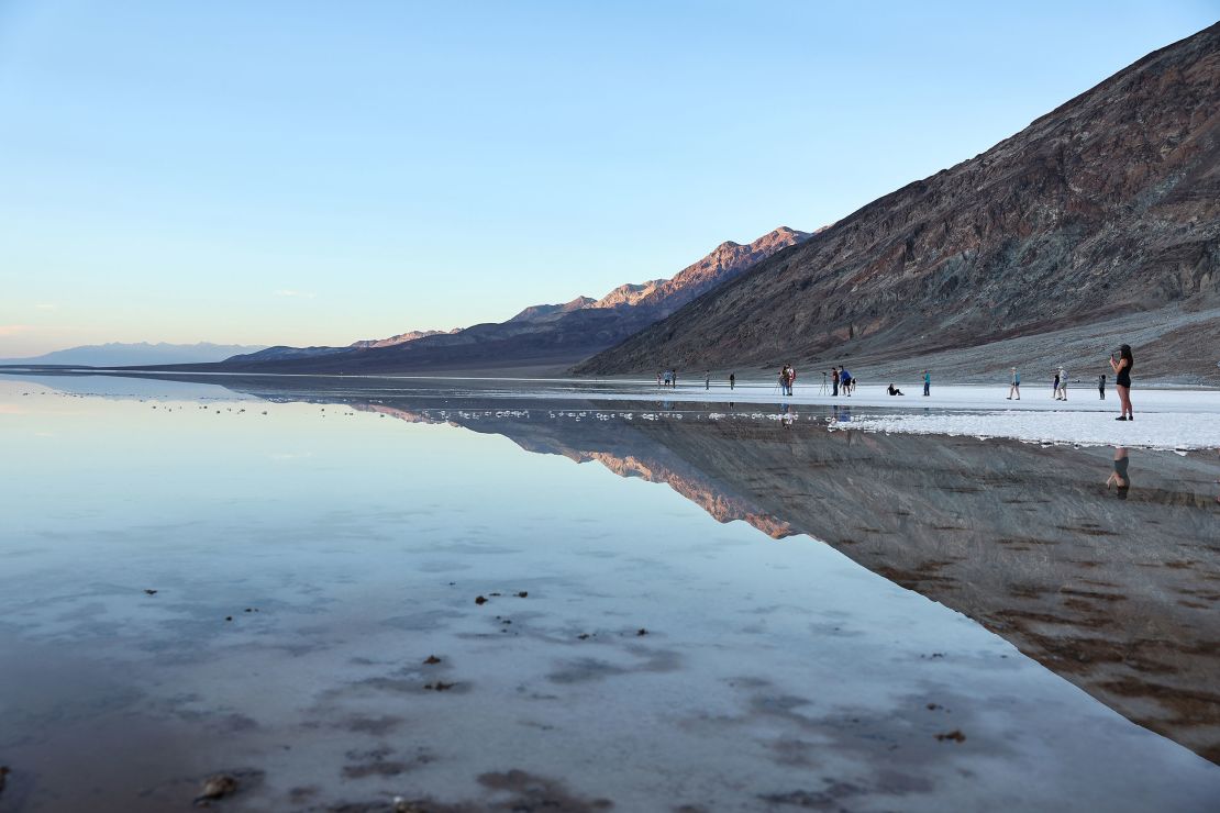 Посетителите се събират в обширното краткотрайно езеро в солниците Badwater Basin в неотдавна отворения още веднъж Национален парк Death Valley на 21 октомври 2023 г.