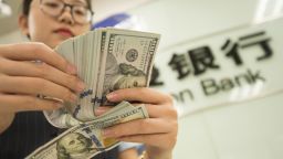 A Chinese clerk counts US dollar notes at a bank in Hai'an city, Nantong city, east China's Jiangsu province, 6 August 2019. 