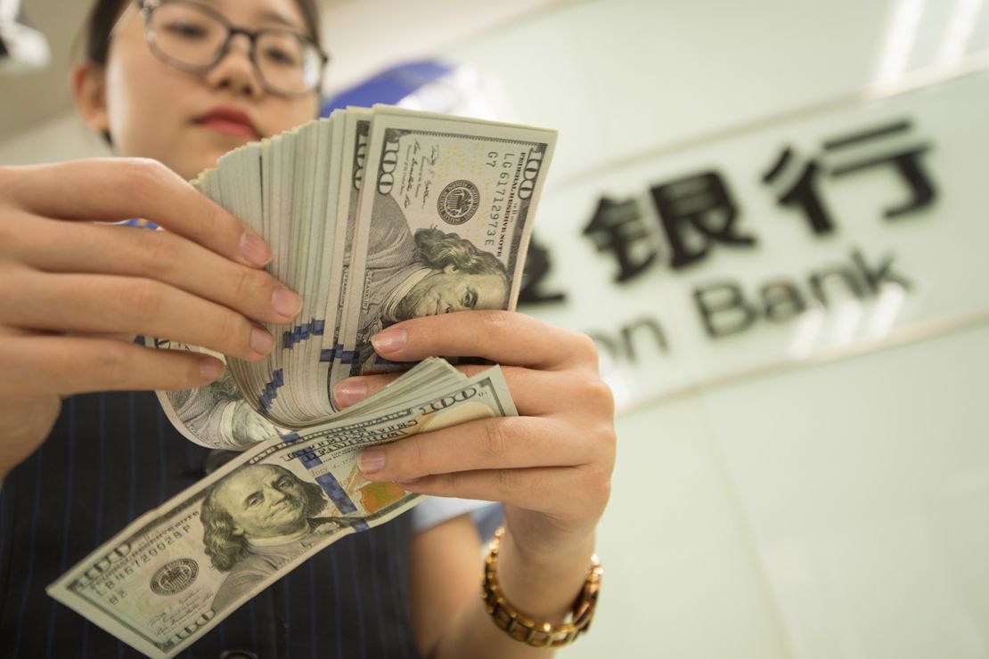 A Chinese clerk counts US dollar notes at a bank in Hai'an city in east China's Jiangsu province on  August 6, 2019. 