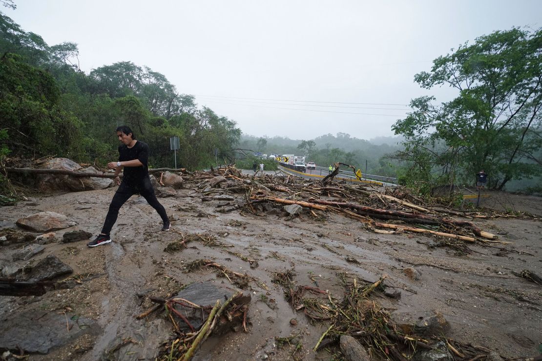 A man crosses a highway blocked by a landslide triggered by Hurricane Otis near Acapulco, Mexico, Wednesday, Oct. 25, 2023. 
