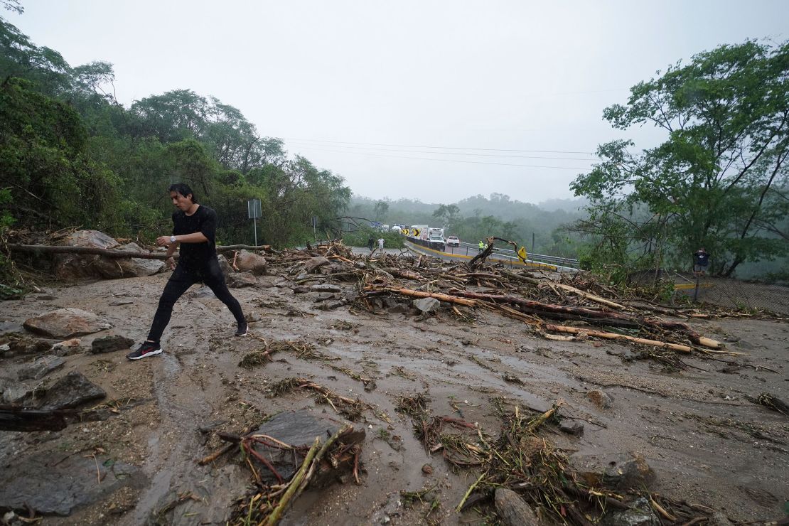 A man on Wednesday crosses a highway blocked by a landslide triggered by Hurricane Otis near Acapulco.