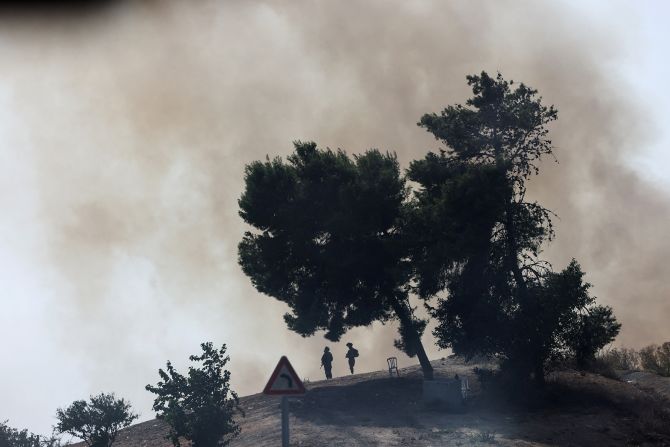 Israeli soldiers stand guard as smoke rises following a rocket launched in southern Israel, on October 24.