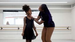 Ruth Essel, 30, founder of Pointe Black Ballet School, and Kioni, 10, rehearse during class whilst an onlooker watches through the window in London, Britain, August 4, 2023. It was a pointed comment about her Afro-braided hair that spurred Essel to carve out what she calls a safe space for Black dancers. The founder of Pointe Black Ballet School in London said when she was a child, teachers and assistants all but punished her for not fitting the traditional ballerina mould, as if she was using her race as some kind of rebellion. Those challenges inspired Essel, a deputy programme manager at a unit of the Royal College of Psychiatrists, to establish Pointe Black in 2020 at the age of 26. "I wanted there to be a Black environment. I wanted there to be people who looked like me. I wanted there to be a teacher that looked like me," she said.       REUTERS/Alishia Abodunde        SEARCH "ABODUNDE BALLET SCHOOL" FOR THIS STORY. SEARCH "WIDER IMAGE" FOR ALL STORIES.    TPX IMAGES OF THE DAY
