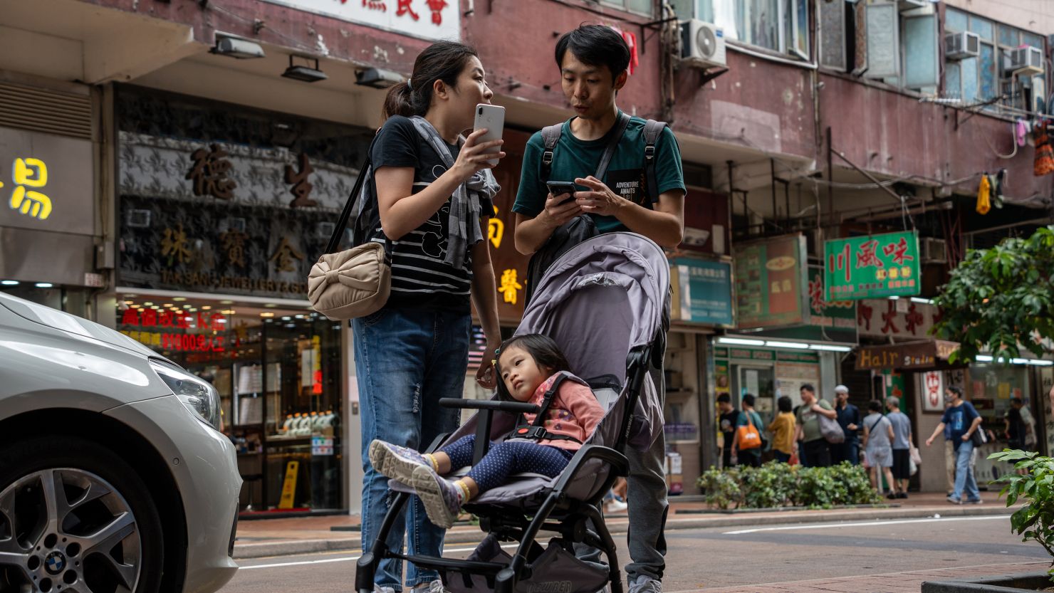 A man and women stand next to a baby in a stroller in Hong Kong 