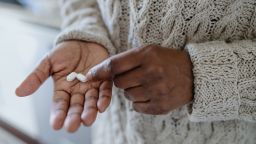 Close-up of a woman holding pills in the palm of her hand.