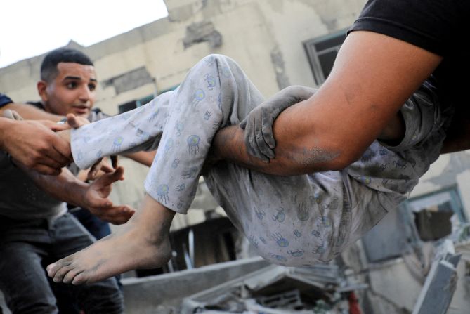 A Palestinian child is assisted as people search for casualties at the site of an Israeli strike on a residential building in Gaza City on October 25.