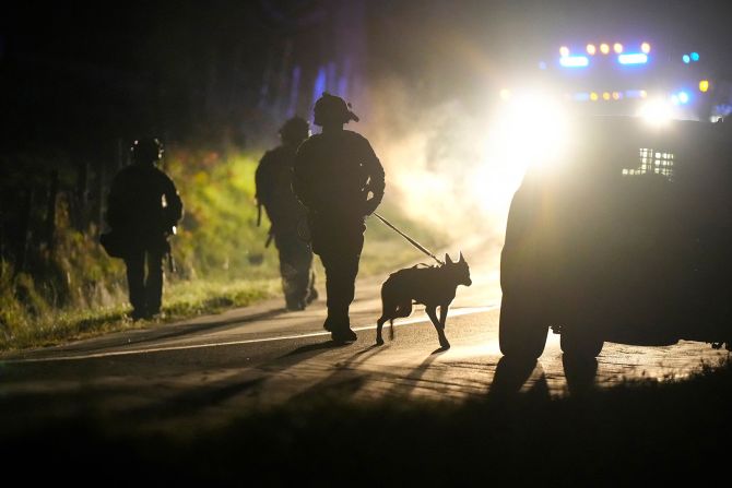 A member of law enforcement walks with a police dog outside a property in Bowdoin on Thursday.