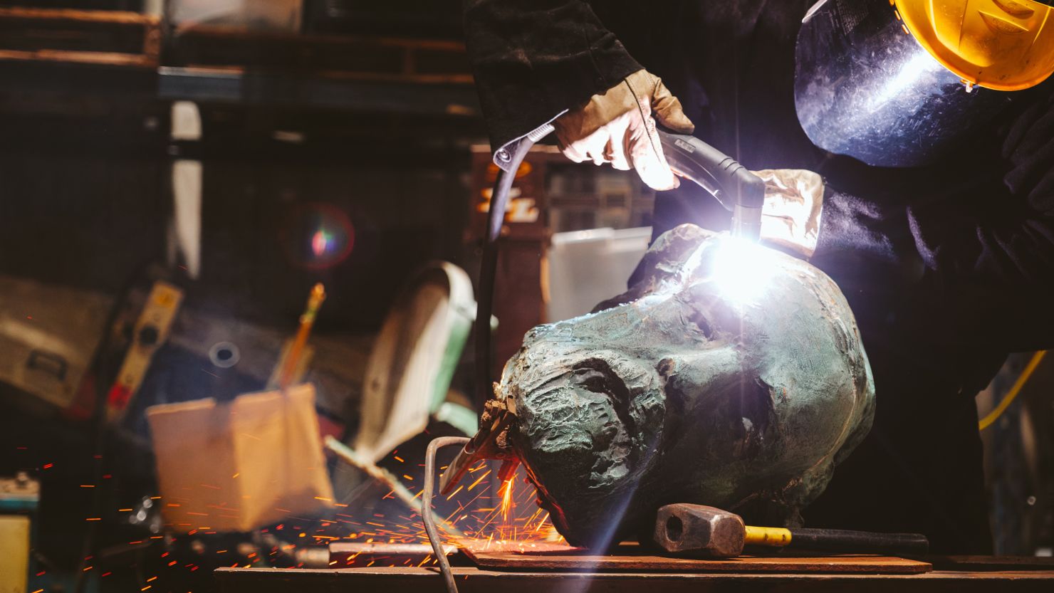 A foundry worker using a plasma torch prepares to cut the head of Charlottesville's bronze monument of Robert E. Lee in preparation for melting the statue. October 21, 2023. Photo by Eze Amos