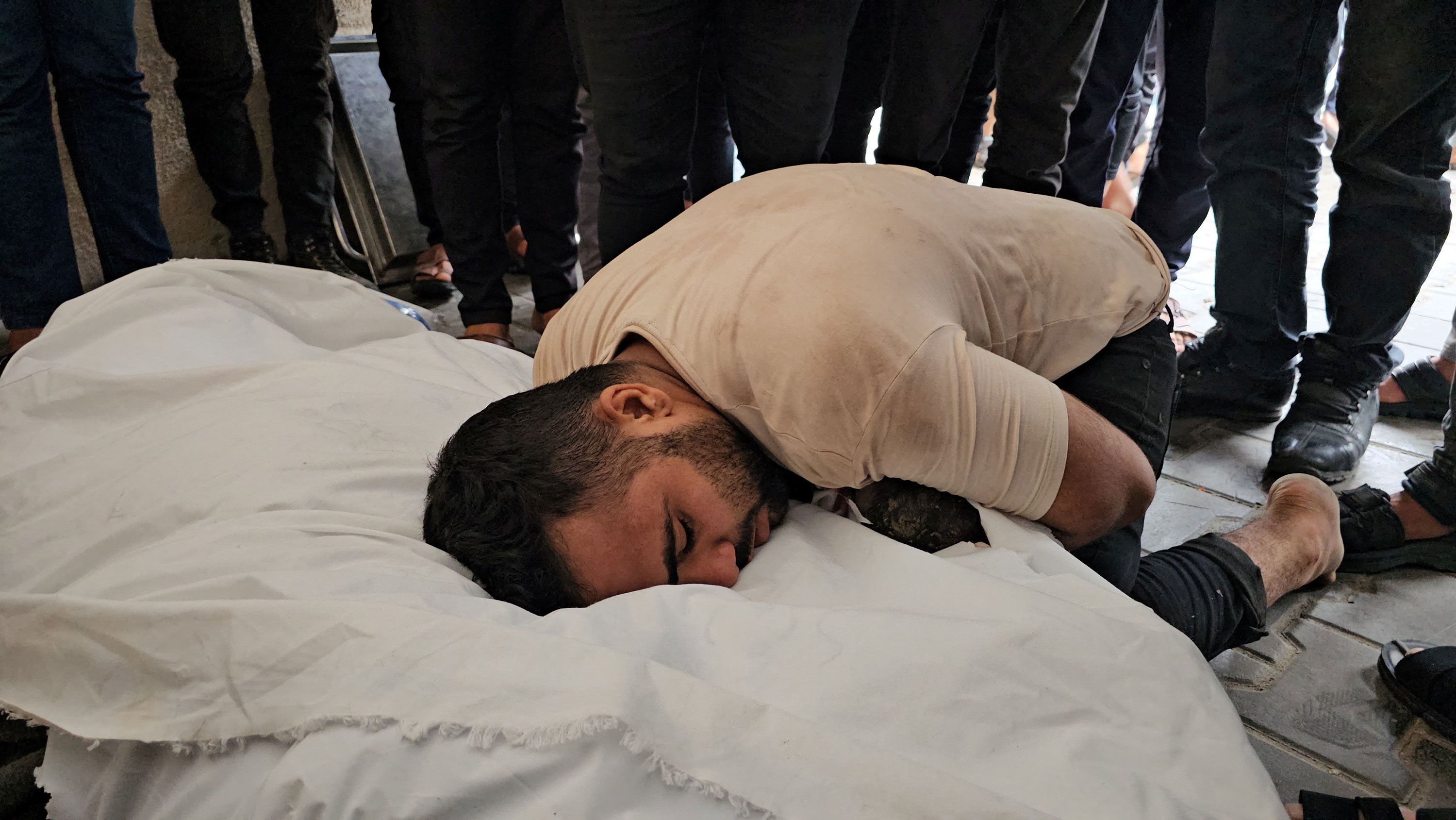 Palestinian lawyer Jehad Al-Kafarnah, whose pregnant wife and unborn child were killed in an Israeli strike, according to health officials, mourns over her shrouded body at a hospital in northern Gaza on Friday, October 27.