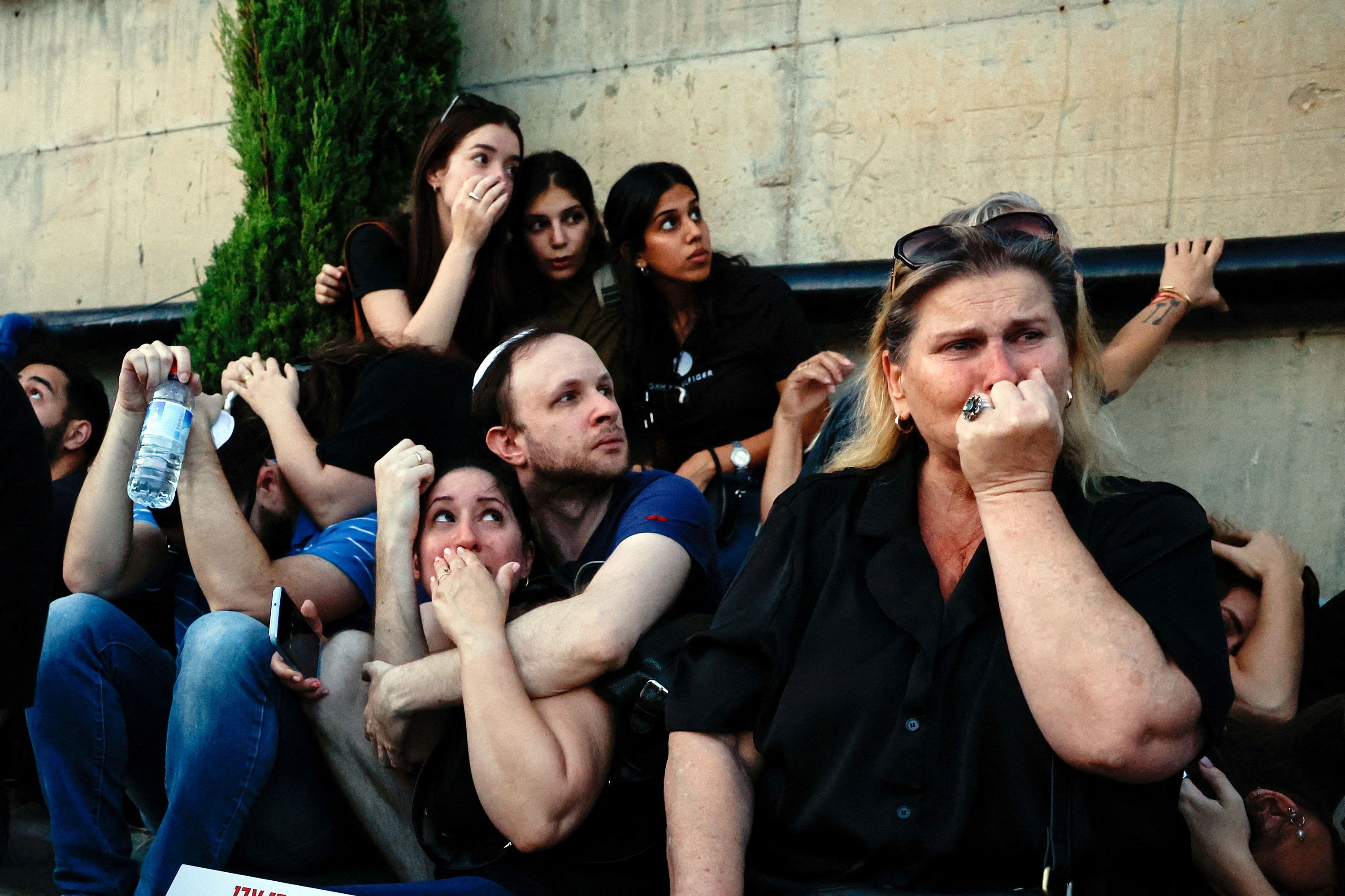 People take cover as rocket sirens sound during the funeral of Sagiv Ben Zvi in Holon, Israel, on Thursday, October 26.