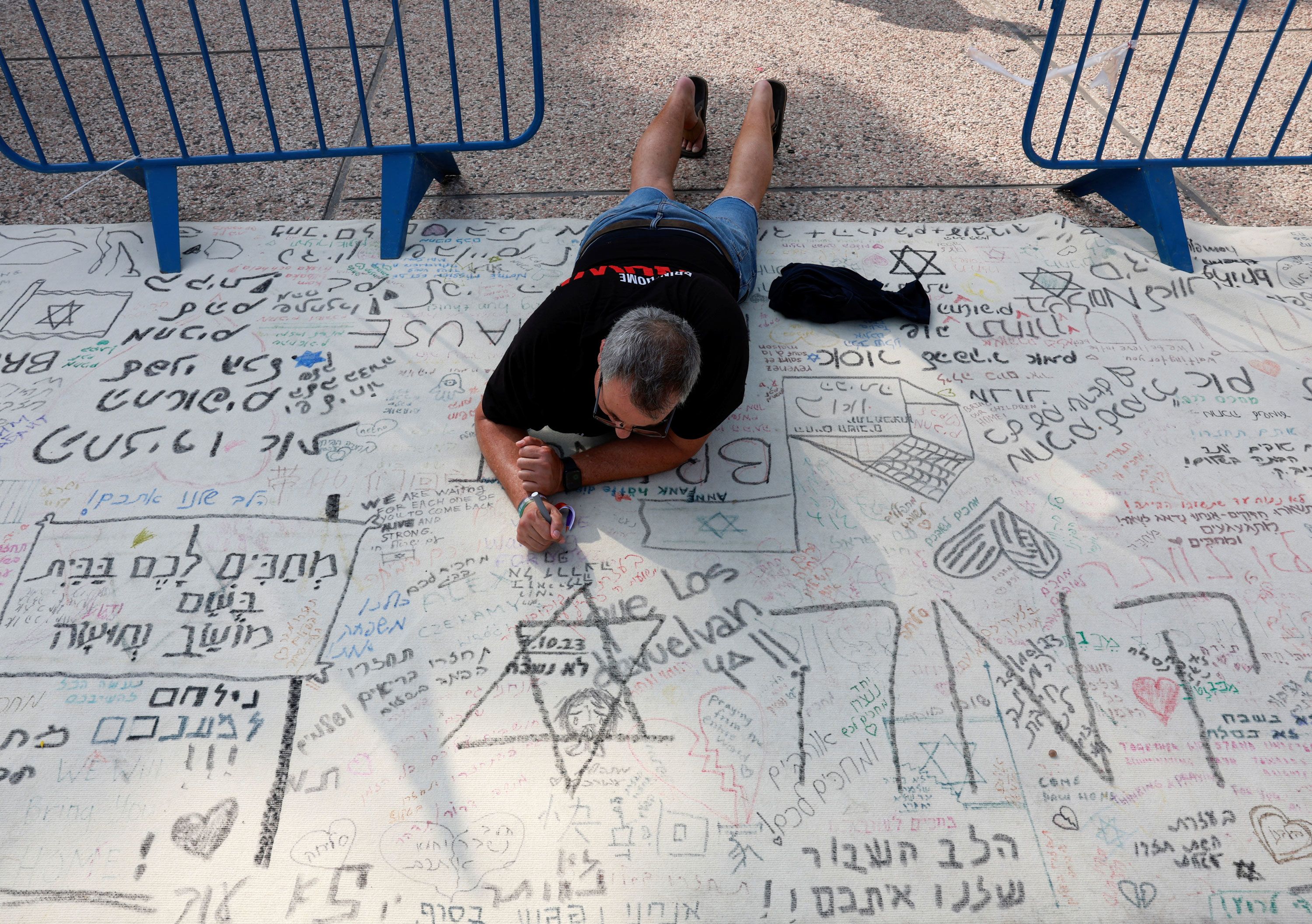 A man writes a message during a demonstration by family members and supporters of hostages who are being held in Gaza after they were kidnapped from Israel by Hamas gunmen, as they call for a dialogue with Israeli Prime Minister Benjamin Netanyahu and Defense Minister Yoav Gallant, in Tel Aviv, Israel on October 28.